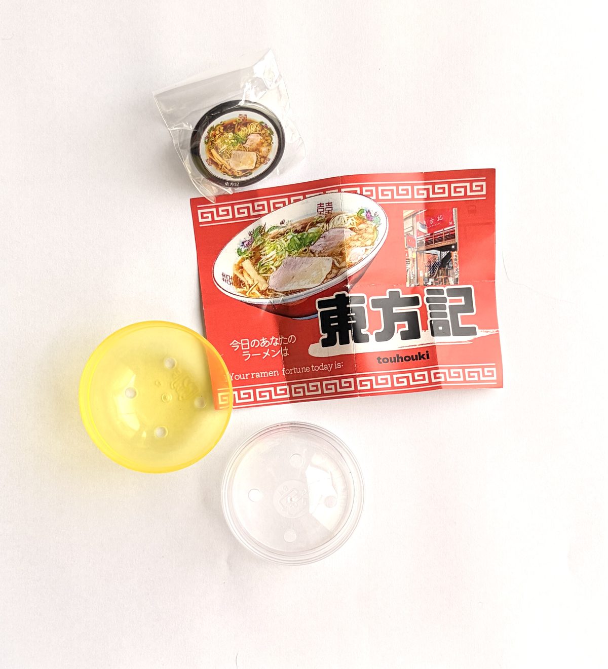 カプセルの中身：お店の紹介カードと缶バッジ